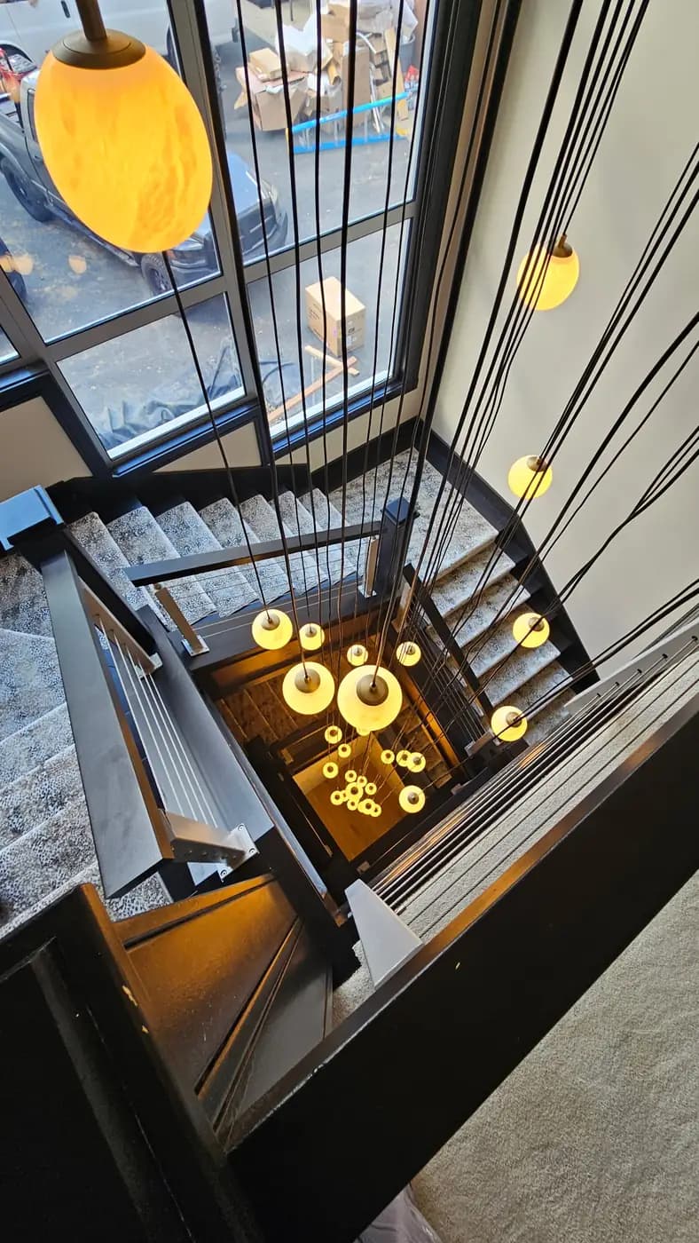 Finished stairwell with cable railing and pendant lights